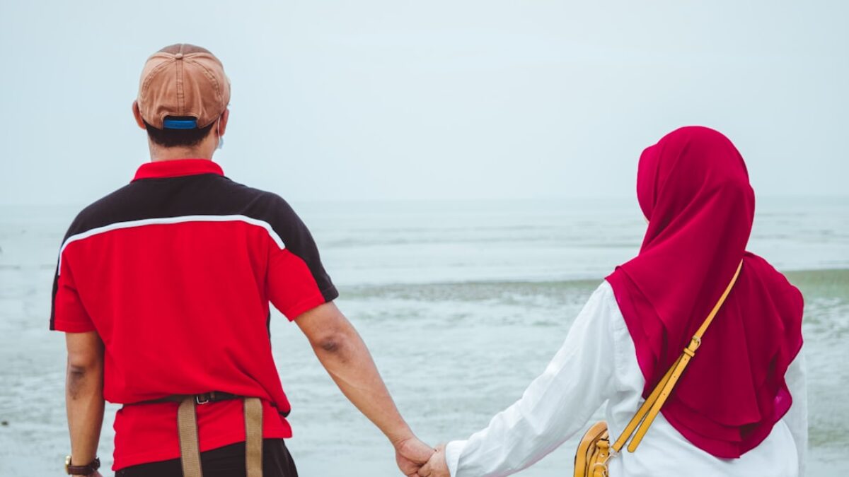 a man and a woman holding hands on the beach