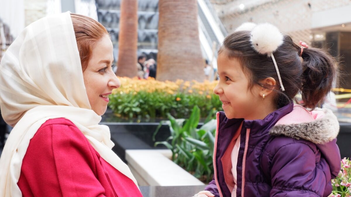 woman in red jacket sitting beside boy in blue jacket